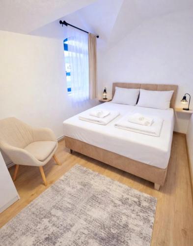 a bedroom with a large white bed and a chair at Stan na dan Bumbar in Kostajnica