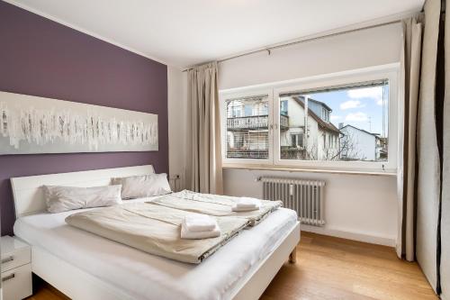 a bedroom with a white bed and a window at Ferienwohnung Morgensonne - modern und freundlich in zentraler Lage in Langenargen