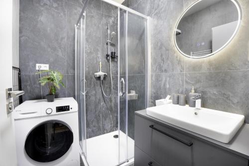 a bathroom with a washing machine and a sink at Calmora apartment Optická WiFi Klimatizace Balkon Nespresso in Komárov