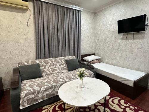 a living room with a couch and a table at Marvarid Hotel in Ghijduwon