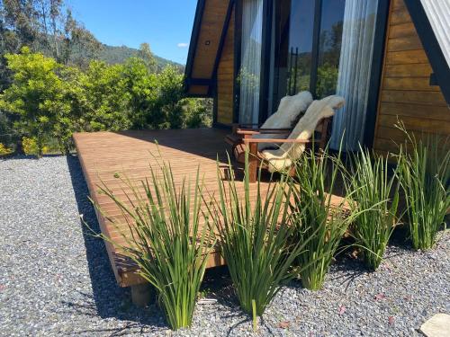 a cabin with a deck with a chair and some plants at Chalés Sol da Serra in Rio Rufino
