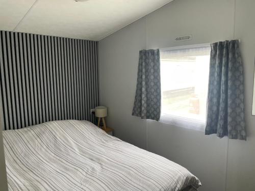 a bedroom with a bed and a window at Alberta holiday park in Whitstable