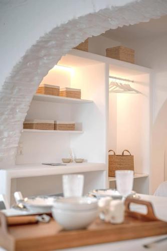 a table with white bowls and plates on it at Suite Amalaya Κατώι in Kithnos