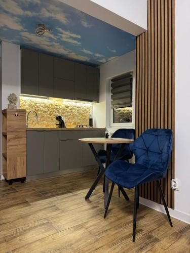 a kitchen with a table and blue chairs at Woodxury in Petrila