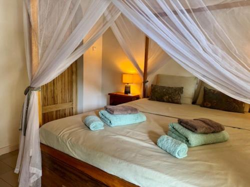 a bedroom with a canopy bed with two pillows at Le Jardin du Saloum in Toubakouta