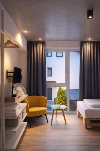 a bedroom with a bed and a yellow chair and a window at Hofgut Stefan - BIO, Bodenständig, Bodensee in Uhldingen-Mühlhofen