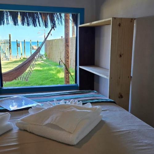 a bedroom with a bed with a window and a hammock at Vila Ohana Beira Mar - Caraíva in Caraíva