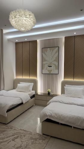 a bedroom with two beds and a chandelier at شقه ثلاث غرف بحي المروه in Jeddah
