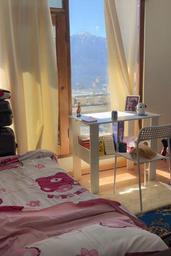 a bedroom with a table and a window with a view at Lhamus homestay in Tawang