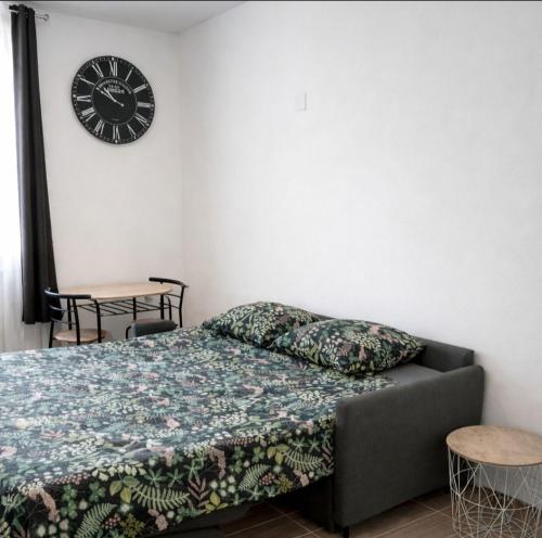 a bedroom with a bed and a clock on the wall at Le Cocon du Ventoux Studio cosy à Carpentras in Carpentras