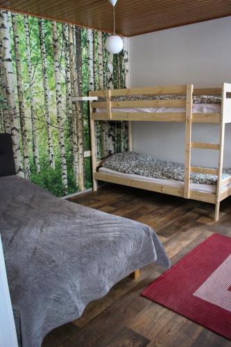 a bedroom with two bunk beds and a tree mural at Hostelli Havumaja in Puumala