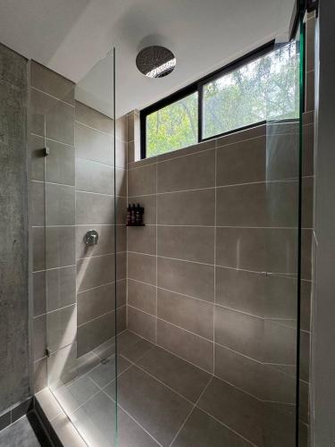 a glass shower in a bathroom with a window at Akela Park Hotel in Medellín
