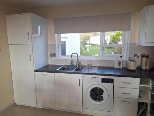 a kitchen with a sink and a washing machine at Gweedore Seaview Cottage in Bun na Leaca