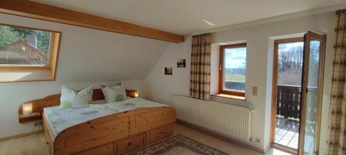 a bedroom with a wooden bed and two windows at Forsthaus Stagnieß in Ueckeritz