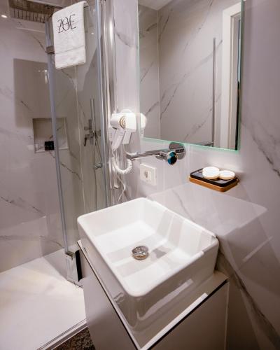 a white bathroom with a sink and a mirror at Zoe Hotel in Prishtinë