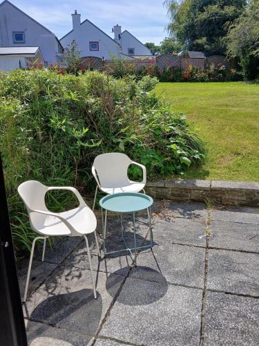 two white chairs and a table on a sidewalk at Thrush Cottage in Schull