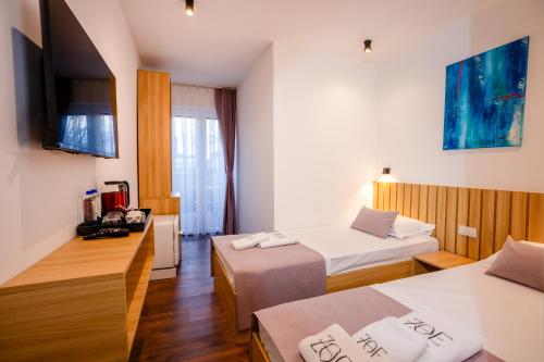 a hotel room with two beds and a television at Zoe Hotel in Prishtinë