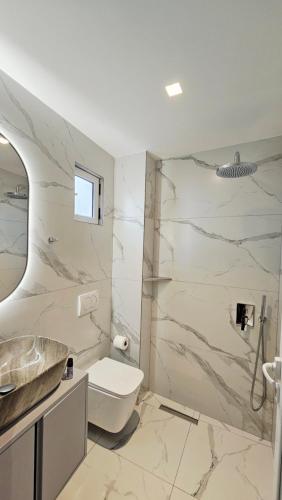 a white bathroom with a sink and a toilet at ARILEO ROOMs in Himare