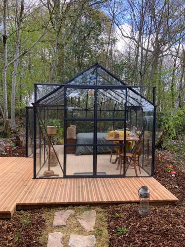 a greenhouse with a table in it on a wooden deck at Le refuge du Jardinier in Abzac