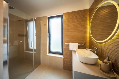 a bathroom with a sink and a mirror and a shower at Villa Carbonia in Kolan