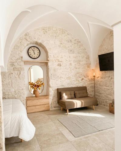 a bedroom with a couch and a clock on a wall at Almurigini I Boutique House I Ceglie Messapica in Ceglie Messapica