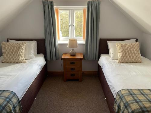 two twin beds in a room with a window at Bwlch Cottage in Gwaynynog