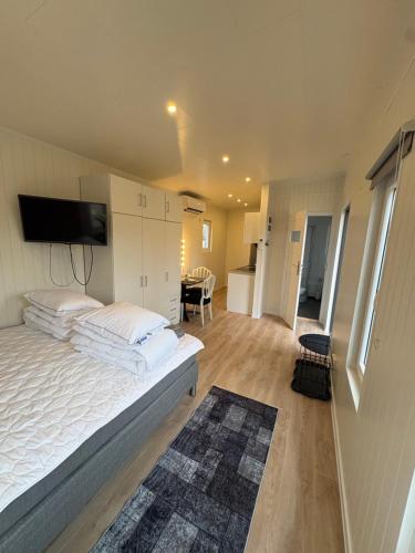 a bedroom with a large bed and a kitchen at Mayas Stuga in Sölvesborg