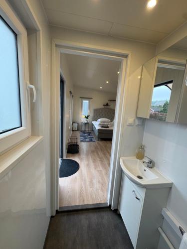 a bathroom with a sink and a mirror and a bedroom at Mayas Stuga in Sölvesborg