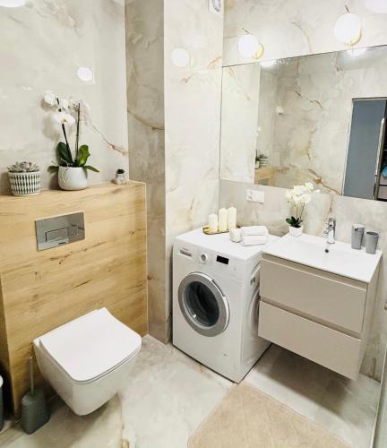 a bathroom with a washing machine and a sink at Lotus Apartments Impero separate kitchen two rooms parking balcony in Ostrołęka