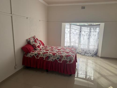 a bedroom with a bed with a red blanket and a window at Albam residency kuruman in Kuruman