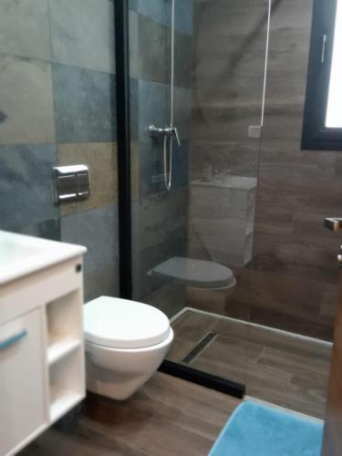 a bathroom with a toilet and a glass shower at Esmeralda in Douar el Hafey