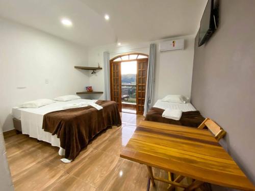 a bedroom with two beds and a wooden bench at Pousada Morada do Sol in Socorro