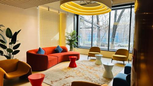 a living room with a red couch and chairs at Renion Almaty Hotel in Almaty