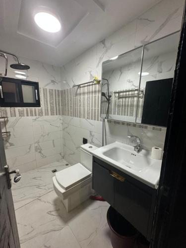 a white bathroom with a toilet and a sink at La MAISON SEONE PREMIUM in Abidjan