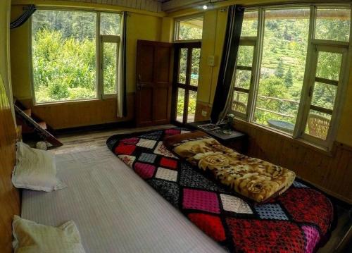 a bedroom with a large bed in a room with windows at Moksh Jibhi Retreat in Jibhi
