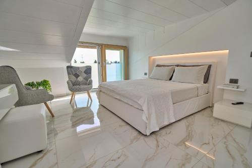 a white bedroom with a bed and a chair at SunStyle House Villetta Rimini con Giardino e Park in Casalecchio