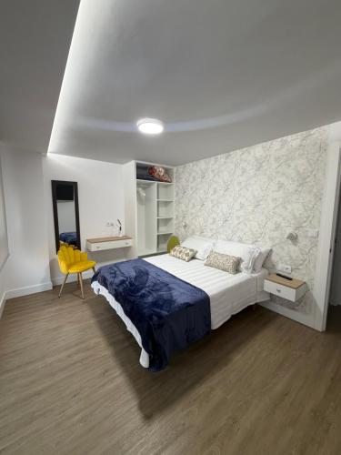a bedroom with a large bed and a yellow chair at Casa da Fonte in Rianjo