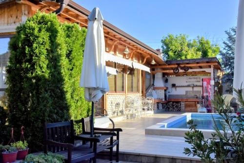 a patio with an umbrella and a swimming pool at Guest house Zlateya in Madara