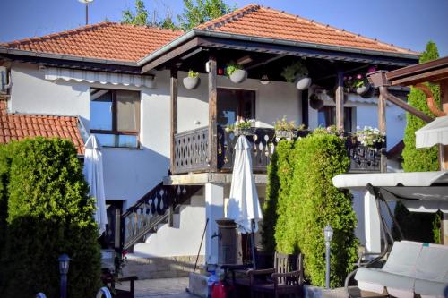 a white house with a balcony with umbrellas at Guest house Zlateya in Madara