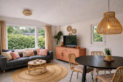 a living room with a couch and a table at Natuurhuisje in het bos met rustige ligging en ruime tuin stijlvol ingericht StayatSas Sam in Epe