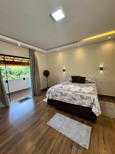 a bedroom with a bed and a large window at Suítes Mazzioni in Socorro