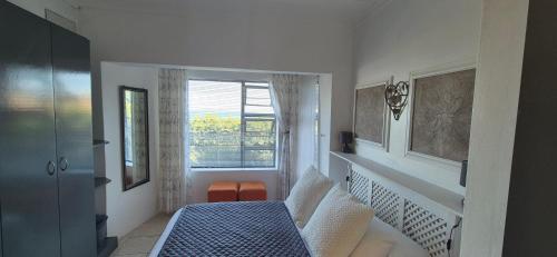 a bedroom with a bed and a window at To C Garden Cottage in Mossel Bay