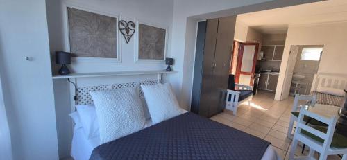 a bedroom with a bed and a living room at To C Garden Cottage in Mossel Bay