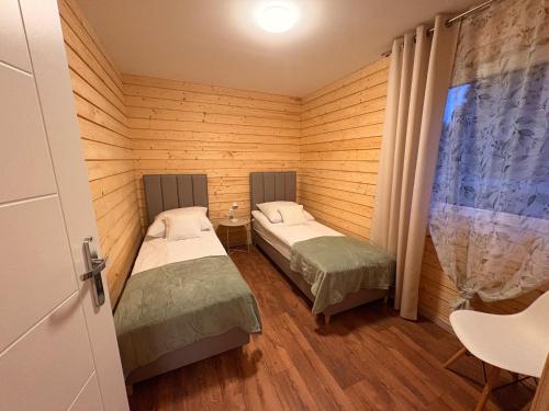 two beds in a room with wooden walls at Accommodation under the Oaks in Dramino