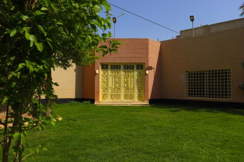 a building with a yellow door and a grass yard at Lemon Tree Guest House in Riyadh
