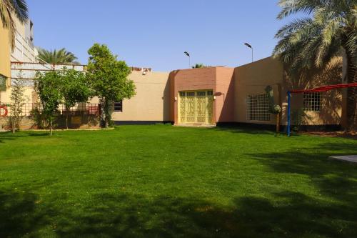 a building with a green yard with a building at Lemon Tree Guest House in Riyadh