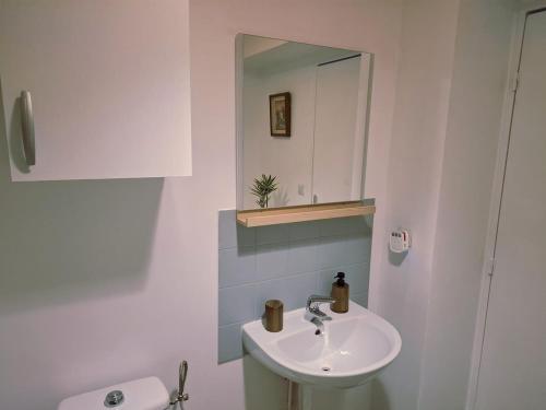 a white bathroom with a sink and a mirror at Studio moderne 33m2 Design cosy Wi Fi gratuit in Courcouronnes