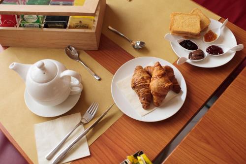 a table with two plates of food and a teapot and bread at Hotel Continental in Reggio Calabria