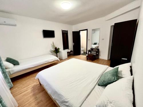 a white room with two beds and a television at Vila Macris in Eforie Nord