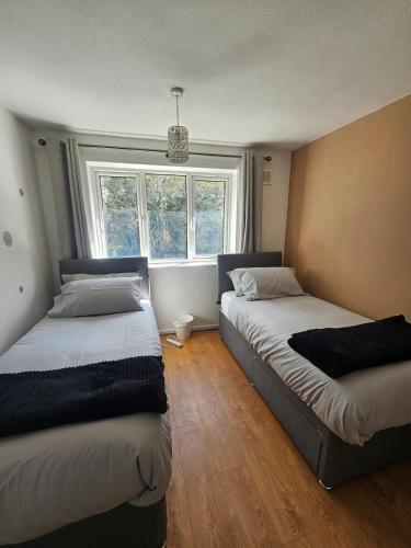 two beds in a room with a window at Valgor -3 Bedroom House-Sleeps 5 with free parking-Ideal for contractors, families and group stays-WV6 in Tettenhall